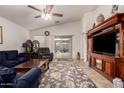 Comfortable living room with neutral walls, a ceiling fan, a large rug and a sliding glass door to the backyard at 18415 W Surprise Farms N Loop, Surprise, AZ 85388