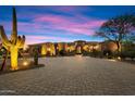 Elegant home exterior with stunning desert landscaping, circular driveway, and warm lighting at twilight at 22610 N 80Th Pl, Scottsdale, AZ 85255