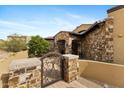 Stone entryway with a gated courtyard that leads to a beautiful wood front door, surrounded by desert plants at 3553 N Crystal Peak Cir, Mesa, AZ 85207