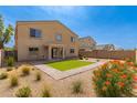 Expansive backyard featuring desert landscaping, green lawn, and covered patio at 42796 W Wild Horse Trl, Maricopa, AZ 85138