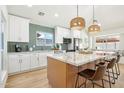 Modern kitchen with an island, pendant lighting, white cabinets and stainless steel appliances at 7204 W Mcrae Way, Glendale, AZ 85308