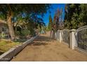 A long driveway is framed by green bushes and a white fence leading to the house at 7804 S 15Th Ave, Phoenix, AZ 85041