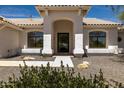 Stunning home entrance with an arched doorway, large windows, and desert-style landscaping at 8156 E Questa Rd, Scottsdale, AZ 85255