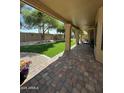 Covered patio with brick flooring overlooks a lush backyard with artificial grass at 9733 W Mcrae Way, Peoria, AZ 85382