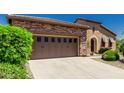 Two car garage with desert landscaping, a walkway and a stone facade to the left of the front door at 13052 W Mine Trl, Peoria, AZ 85383