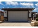 Home exterior showcasing a two-car garage with a modern design and stone accents at 17437 W Via De Luna Dr, Surprise, AZ 85387