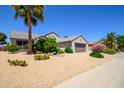 Well-maintained desert home with desert landscaping, palm trees, and a spacious driveway with a two car garage at 19892 N Shadow Mountain Dr, Surprise, AZ 85374