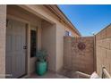 Welcoming front porch area with a potted plant and decorative sunburst wall art at 38662 N La Grange Ln, San Tan Valley, AZ 85140