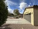 Side view of a home showing the two-car garage and low maintenance desert landscaping with neutral-tone stucco exterior at 4440 S Leisure Way, Gilbert, AZ 85297