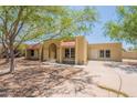 Tan single-story home featuring an arched entryway, desert landscaping, and a concrete driveway at 717 W Chilton St, Chandler, AZ 85225