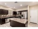 Well-lit kitchen featuring an island, stainless steel appliances, and dark cabinetry at 7769 W Bonitos Dr, Phoenix, AZ 85035