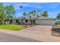 Inviting one-story home showcasing a lush green lawn, mature trees, and a spacious driveway leading to a two-car garage at 8582 E Via De Dorado --, Scottsdale, AZ 85258