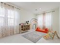 Bright playroom with rainbow wall art, a cozy rug, and large windows, perfect for activities at 10034 E Thunderbolt Ave, Mesa, AZ 85212