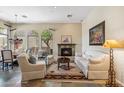 Cozy living room featuring a stone fireplace and large windows with backyard views at 11462 E Kora Way, Scottsdale, AZ 85255