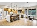 Modern kitchen with large island, bar stool seating, pendant lights, and stainless steel appliances next to dining area at 14049 S 8Th St, Phoenix, AZ 85048