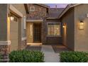 Close-up of the house entrance, highlighting the stone accents, well-lit doorway, and manicured shrubbery at 21283 E Camacho Rd, Queen Creek, AZ 85142