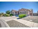 Home featuring a three-car garage, stone veneer accents, well-manicured landscaping, and a spacious driveway at 21551 E Waverly Ct, Queen Creek, AZ 85142