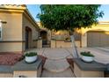 Charming front exterior featuring a lovely tree, a gated entrance, and potted plants at 23213 N Del Monte Dr, Sun City West, AZ 85375