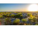 A scenic aerial shot showcases a modern home nestled among lush desert foliage with mountain views at 24066 N 90Th Way, Scottsdale, AZ 85255