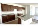 An unfinished kitchen features dark brown cabinets, granite countertops, and a center island with a sink at 5633 S 253Rd Ave, Buckeye, AZ 85326