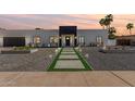 Modern exterior showcasing a sleek design with a dark garage door and a stone pathway at 6539 E Sharon Dr, Scottsdale, AZ 85254
