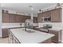 Well-lit kitchen features custom cabinetry, stainless steel appliances, and a large island with seating at 681 W Belmont Red Trl, San Tan Valley, AZ 85143