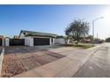 Single-story home with a well-maintained driveway, a black garage door, and a red front door at 7425 W Corrine Dr, Peoria, AZ 85381