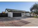 Single-story home with a well-maintained driveway, a black garage door, and a red front door at 7425 W Corrine Dr, Peoria, AZ 85381