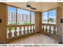 Bright enclosed balcony featuring a ceiling fan, tiled floor, and scenic views of the community's landscaped exterior at 7970 E Camelback Rd # 110, Scottsdale, AZ 85251