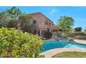 A luxurious home exterior featuring a swimming pool, balcony, and lush landscaping at 8732 W Adam Ave, Peoria, AZ 85382