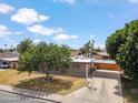 Home exterior featuring a lush shade tree in the front yard and a long driveway leading to a carport at 1308 S Spur --, Mesa, AZ 85204