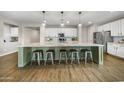 Spacious kitchen featuring a large center island, stainless appliances, white cabinetry and pendant lighting at 20458 W Briarwood Dr, Buckeye, AZ 85396