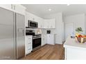 Bright, functional kitchen with stainless steel appliances, white cabinets, and plenty of counter space at 25876 W White Feather Ln, Wittmann, AZ 85361