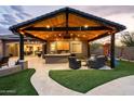 Outdoor kitchen and dining area with a built-in barbecue, bar seating, and comfortable lounge seating at 35971 N Prickley Pear Rd, Cave Creek, AZ 85331