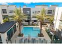 Aerial view of a community pool with palm trees, lounge chairs, and nearby residential buildings at 6850 E Mcdowell Rd # 29, Scottsdale, AZ 85257