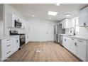 Modern kitchen with white cabinets, stainless steel appliances, quartz countertops, and natural light from the skylight at 16008 N 69Th Ln, Peoria, AZ 85382