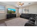 Comfortable living room with a sectional sofa, ceiling fan, and bright natural light at 17802 N 114Th Ln, Surprise, AZ 85378