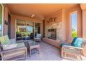 Covered patio with stone fireplace and comfortable wicker furniture perfect for entertaining at 1809 E Adelante Way, Queen Creek, AZ 85140