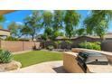 Private backyard featuring artificial grass, desert landscaping, and a built-in grill station at 2031 W Periwinkle Way, Chandler, AZ 85248