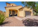 Home with a charming yellow exterior, well-maintained desert landscaping, and a welcoming front entrance at 22184 N 101St Dr, Peoria, AZ 85383