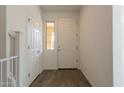 Bright foyer with wood look tile flooring, featuring a white door and staircase at 22184 N 101St Dr, Peoria, AZ 85383