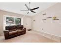 A well-lit living room includes a large window, ceiling fan, and comfortable leather seating at 5135 E Evergreen St # 1159, Mesa, AZ 85205