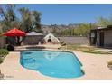 Backyard pool with an outdoor kitchen, umbrellas for shade, and mountain views in the distance at 7232 N 22 Nd St, Phoenix, AZ 85020