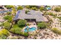 Birds eye view of backyard oasis: pool, spa, outdoor kitchen, mature trees, desert landscaping, and solar panels at 9936 E Winter Sun Dr, Scottsdale, AZ 85262