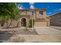 Charming two-story home featuring a well-manicured front yard and a welcoming, covered entry with an arched doorway at 11891 N 147Th Dr, Surprise, AZ 85379