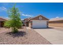 Exterior of tan home with two-car garage, desert landscaping, concrete driveway and security door at 15725 W Lundberg St, Surprise, AZ 85374