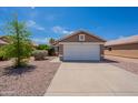 Exterior of tan home with two-car garage, desert landscaping, and concrete driveway at 15725 W Lundberg St, Surprise, AZ 85374
