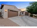 Beautiful home featuring a three-car garage, concrete driveway, and desert landscaping with a view of the sunset at 19905 E Apricot Ln, Queen Creek, AZ 85142