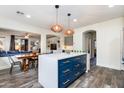 Kitchen island with white countertop, blue cabinets and pendant lighting open to living spaces at 20713 N 91St Dr, Peoria, AZ 85382