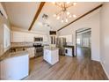 Open kitchen with stainless steel appliances, a kitchen island, white cabinets, and wood laminate flooring at 20802 N 7Th Pl, Phoenix, AZ 85024